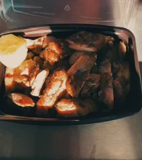 A to-go box of Thai chicken pieces